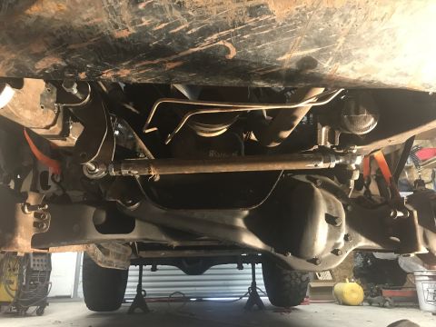 1984 Ford Bronco - Undercarriage view of a vehicle's suspension and drivetrain components, supported by jack stands.