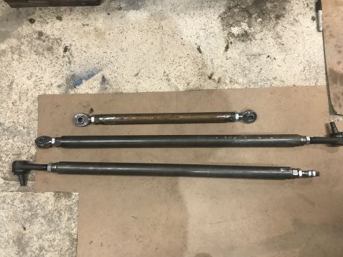 1984 Ford Bronco - Three adjustable steering linkage rods are displayed on a workbench, possibly workshop, floor.
