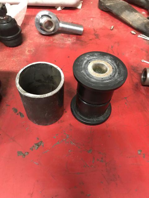 1984 Ford Bronco - Close-up of automotive suspension parts and a metal cylinder on a red workbench.