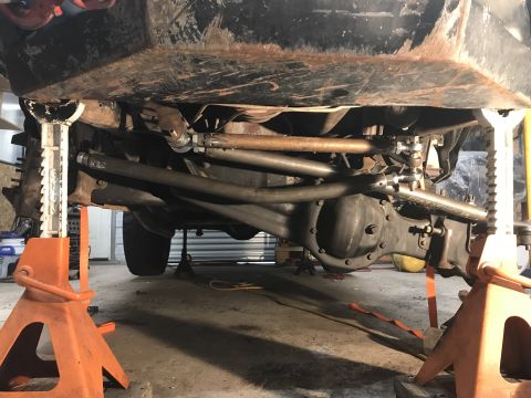 1984 Ford Bronco - Undercarriage view of a vehicle supported by jack stands, revealing its suspension and drivetrain components.