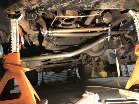 1984 Ford Bronco - Underside view of a vehicle's steering and suspension system, supported by jack stands.