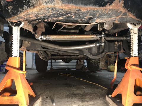 1984 Ford Bronco - Undercarriage of a vehicle supported by jack stands, with a focus on the steering and suspension components.