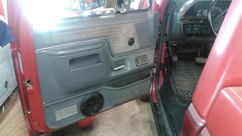 1991 Ford F-150 - Interior view of a red truck's driver side door panel and dashboard, showing the fabric insert and controls.