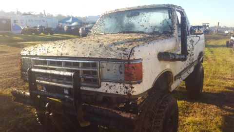 1988 Ford Bronco - This heavily muddied pickup truck appears to be from the late 1980s, possibly a Ford F-series.
