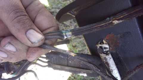 1990 Ford F-250 - A hand inspects damaged wiring, showing frayed insulation and exposed conductors with signs of corrosion.