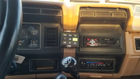 1985 Ford Bronco - The interior dashboard of a 1985 Ford Bronco shows gauges, a digital display, and two radios.
