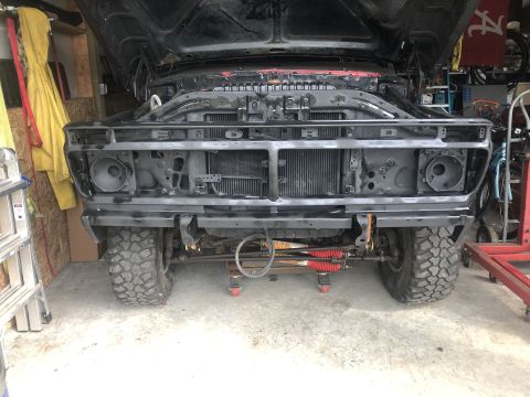 1978 Ford Bronco - Front view of a 1978 Ford Bronco undergoing repairs in a garage, showing the engine bay and suspension.