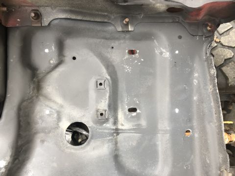 1978 Ford Bronco - The underside of a vehicle, with visible wear and tear, and a portion of a tire on the right side.