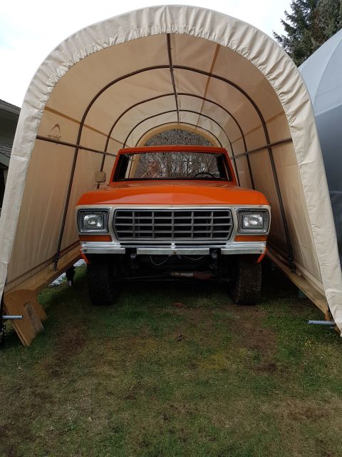 1978 Ford Bronco - An orange pickup truck is parked inside a portable garage, viewed from the front.