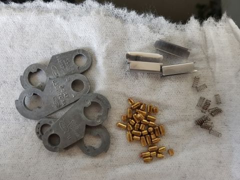 1978 Ford Bronco - Ford ignition lock cylinder parts including pins, springs, and retainer clips are laid out on a white cloth.