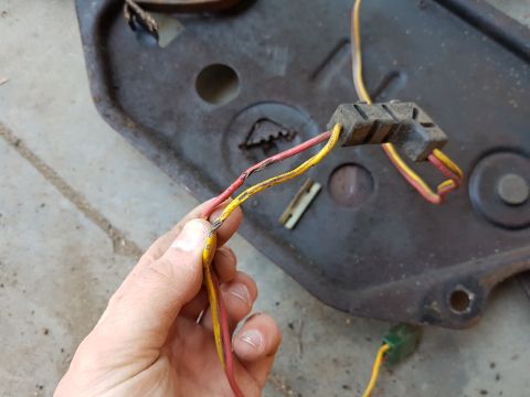 1978 Ford Bronco - Close-up of a damaged wiring harness connector with frayed wires being held by a hand.