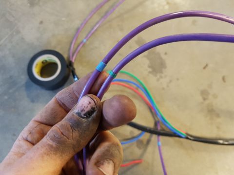 1978 Ford Bronco - Close-up of a hand holding electrical wires, with tape markers visible.