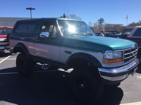 1979 Ford Bronco - This two-tone SUV, likely a 1992 model, is equipped with large off-road tires and fender flares.