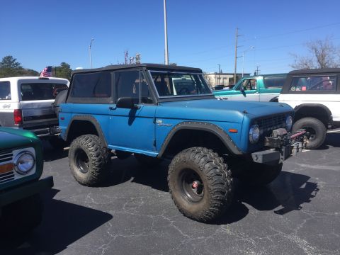 1979 Ford Bronco - A blue Ford Bronco is parked in a lot with other vehicles under a clear sky.