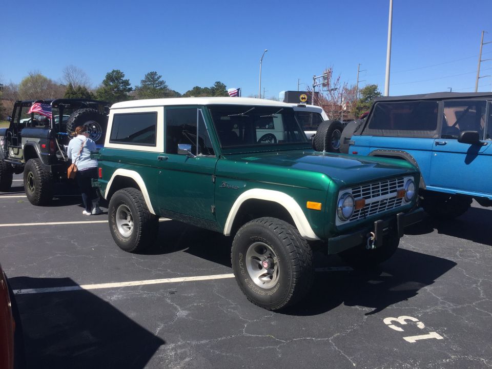 Green 1979 Ford Bronco with white top parked next to other vehicles
