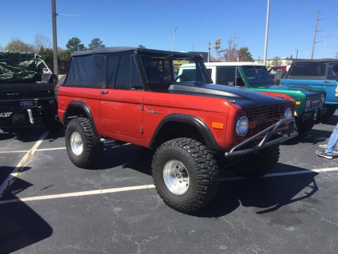 1979 Ford Bronco - Modified red Ford Bronco parked in a lot with other vehicles. The year is likely 1978 based on body style.