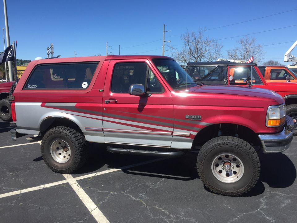 Red and silver Ford Bronco with silver side graphics, lifted suspension, and off-road tires