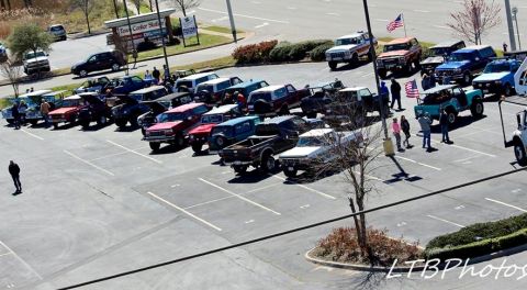1979 Ford Bronco - A gathering of vintage Ford Broncos and trucks fills a parking lot.