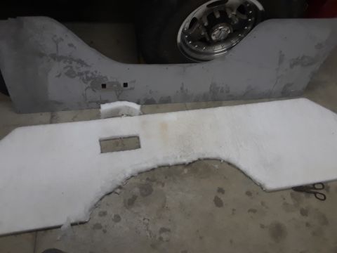 1985 Ford Bronco - A vehicle's interior panel and wheel are shown, with insulation material laid out nearby.