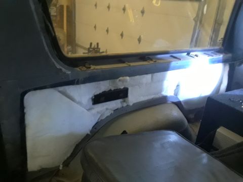 1985 Ford Bronco - The interior of a vehicle shows white insulation being installed around the rear passenger area.