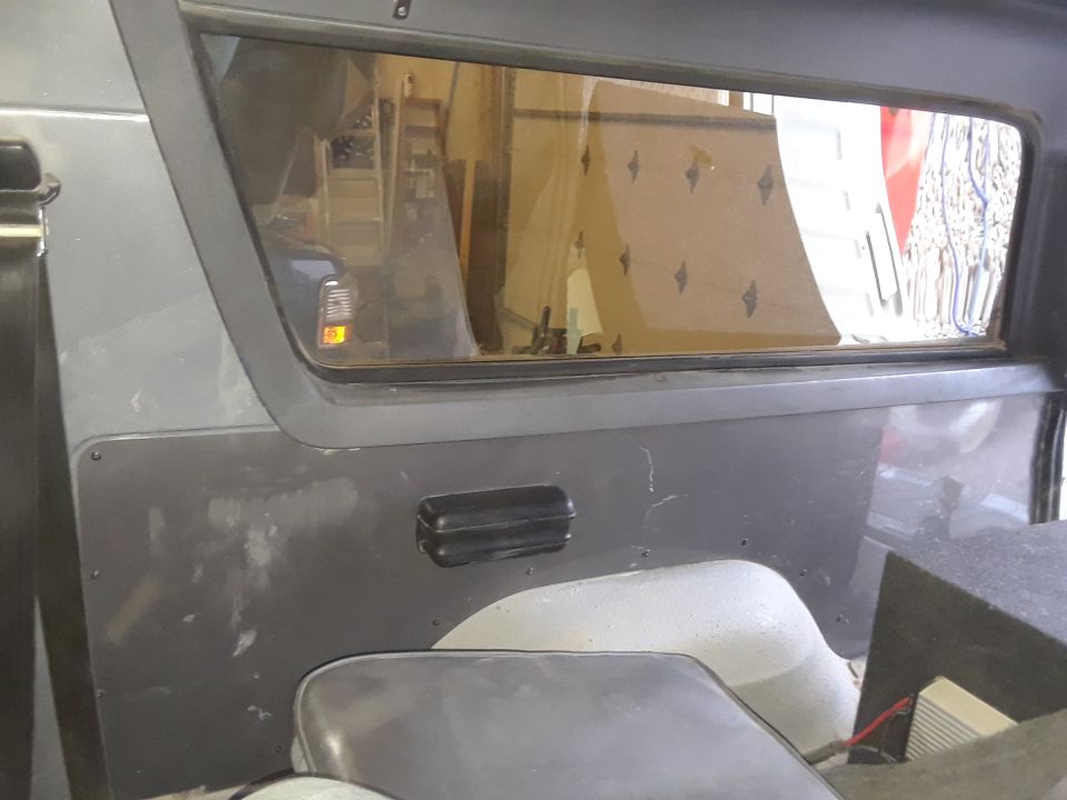 Interior paneling and window of a vehicle, showing a black grab handle