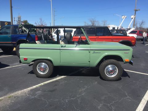 1979 Ford Bronco - Side view of a green 1979 Ford Bronco. Other vehicles are parked nearby.