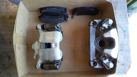 New brake calipers and pads laid out in a cardboard box