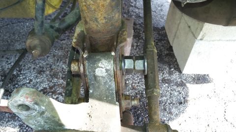 Close-up of rusty car suspension components, including a shock absorber mount and a bolt