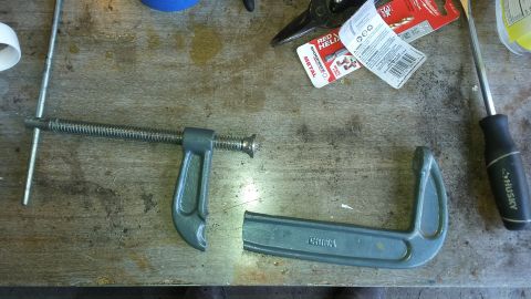 C-clamp, screwdriver, and packaging for drill bits on a workbench