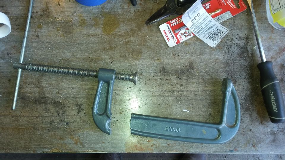 C-clamp, screwdriver, and packaging for drill bits on a workbench