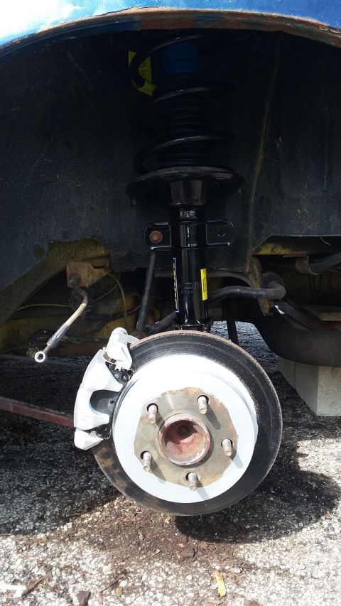 Close-up of a car's front brake rotor, caliper, and strut assembly