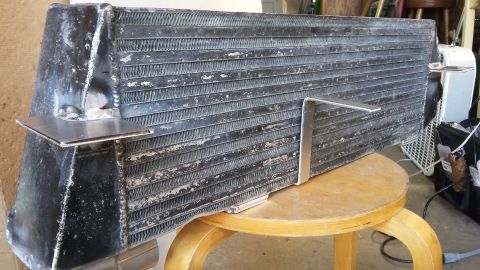 intercooler with metal brackets attached, sitting on a stool