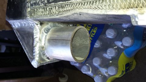 Welded metal pipe protruding from a radiator, with bottles of water in the background