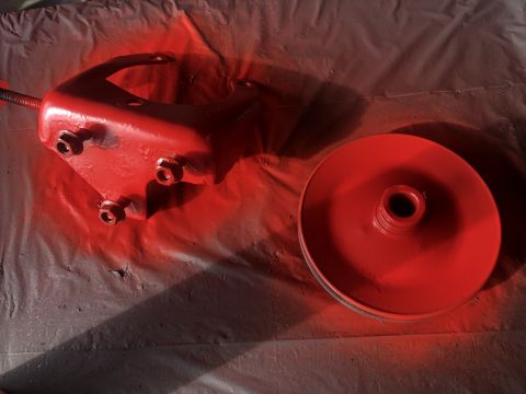 1978 Ford Bronco - Two automotive parts freshly painted red, resting on a drop cloth.