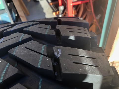 1992 Jeep Wrangler - A close-up view of a tire's aggressive tread pattern, showing blue accent lines and chalk markings on the blocks.