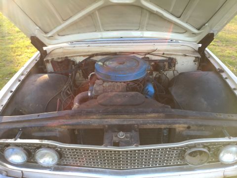 1960 Ford Starliner - The engine compartment of a vintage car, a V8 engine and a prominent blue air filter housing.