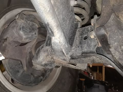 1985 Ford Bronco - Close-up of the front suspension system of a vehicle, showing various mechanical components.