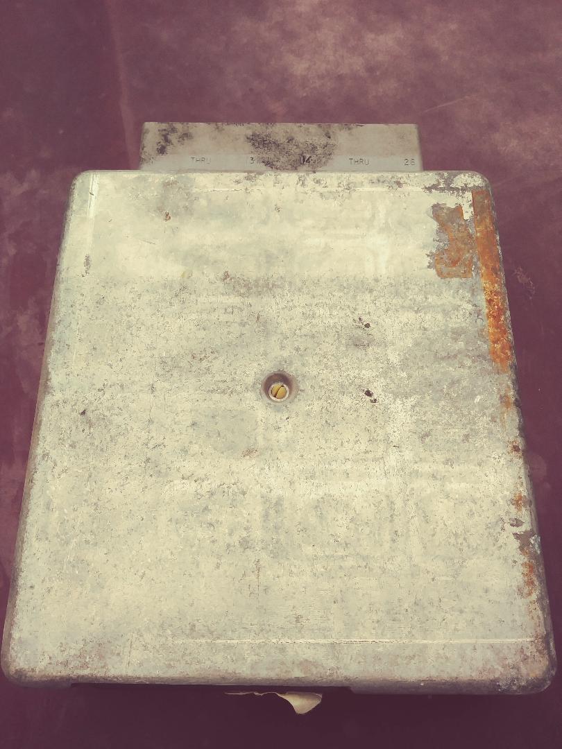 Metal automotive computer module with visible text and rust