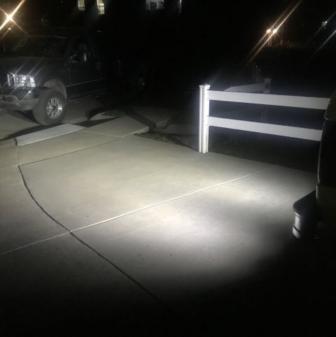 1995 Ford Bronco - A black truck is parked on a concrete driveway at night, its headlights illuminating the area.
