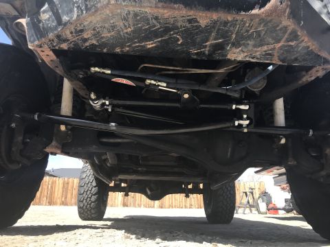 1984 Ford Bronco - The underside of a vehicle is captured from a low angle, revealing its mechanical components and tires.