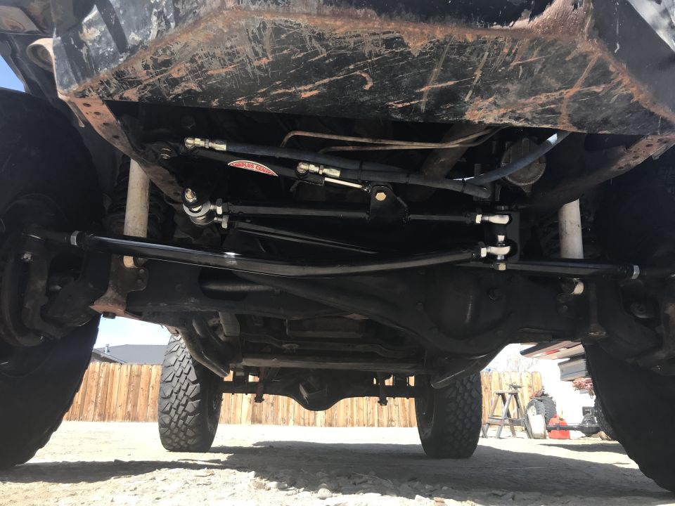 Undercarriage of a vehicle showing steering components and suspension. Tires are visible