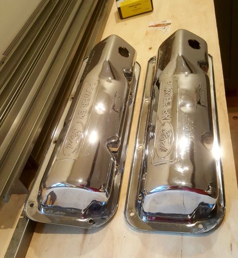 1973 Ford Mustang - A pair of chrome valve covers, each embossed with the Ford logo and 'POWER BY' text, are displayed on a wooden surface.