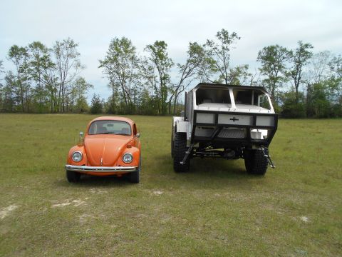 1992 Ford Bronco - Two very different vehicles are parked in a grassy field with trees in the background.