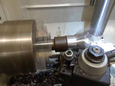 1985 Ford Bronco - A metal part is being shaped on a lathe, with metal shavings accumulating around the machinery.