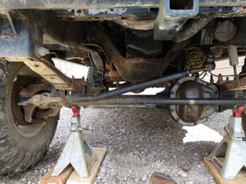1995 Ford Bronco - The underside of a vehicle is shown, focusing on the Dana 60 axle and suspension components, supported by jack stands.