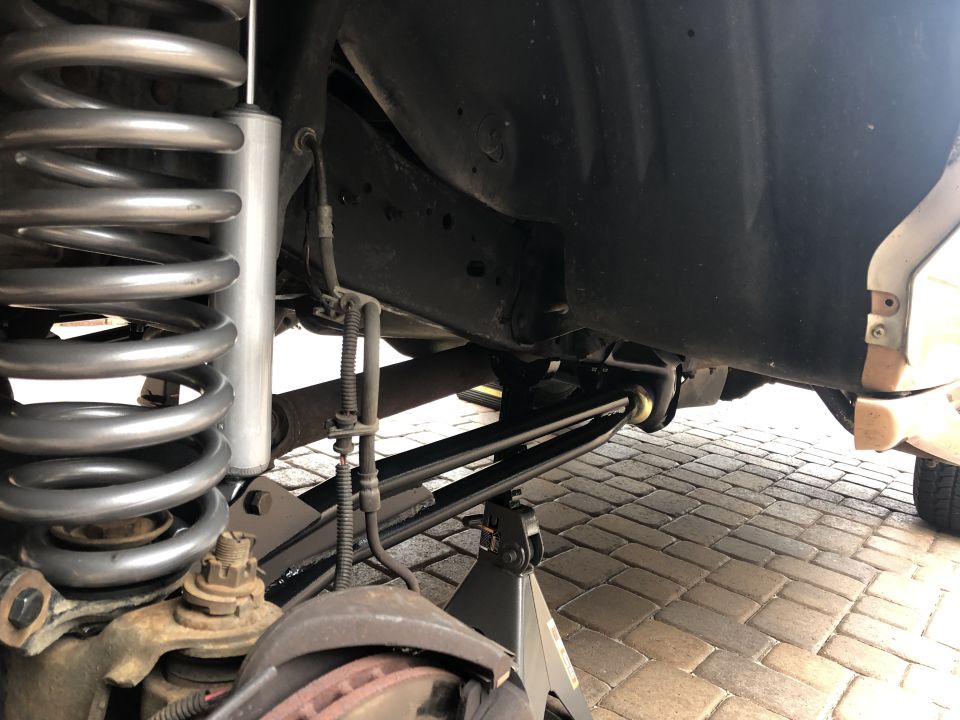 Close-up of a vehicle's rear suspension with a coil spring, shock absorber, and jack stands