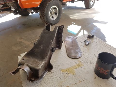 1978 Ford Bronco - Various metal components and a black mug are laid out on a wooden surface.