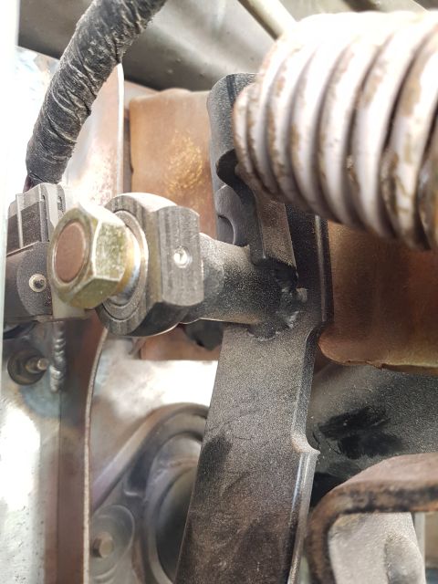1978 Ford Bronco - A close-up view of a mechanical linkage assembly, highlighting a large hex nut and a coiled spring.