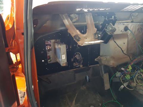 1978 Ford Bronco - The interior of an orange vehicle reveals a disassembled dashboard with exposed wiring and an ECU mounted on the firewall.