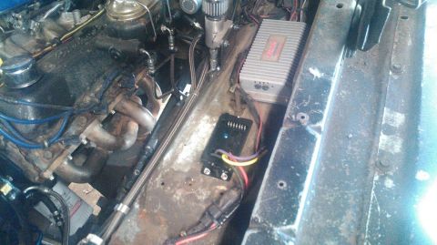 1978 Ford Bronco - Close-up view of a vehicle's engine bay, showing the engine, headers, and installed electronic components.